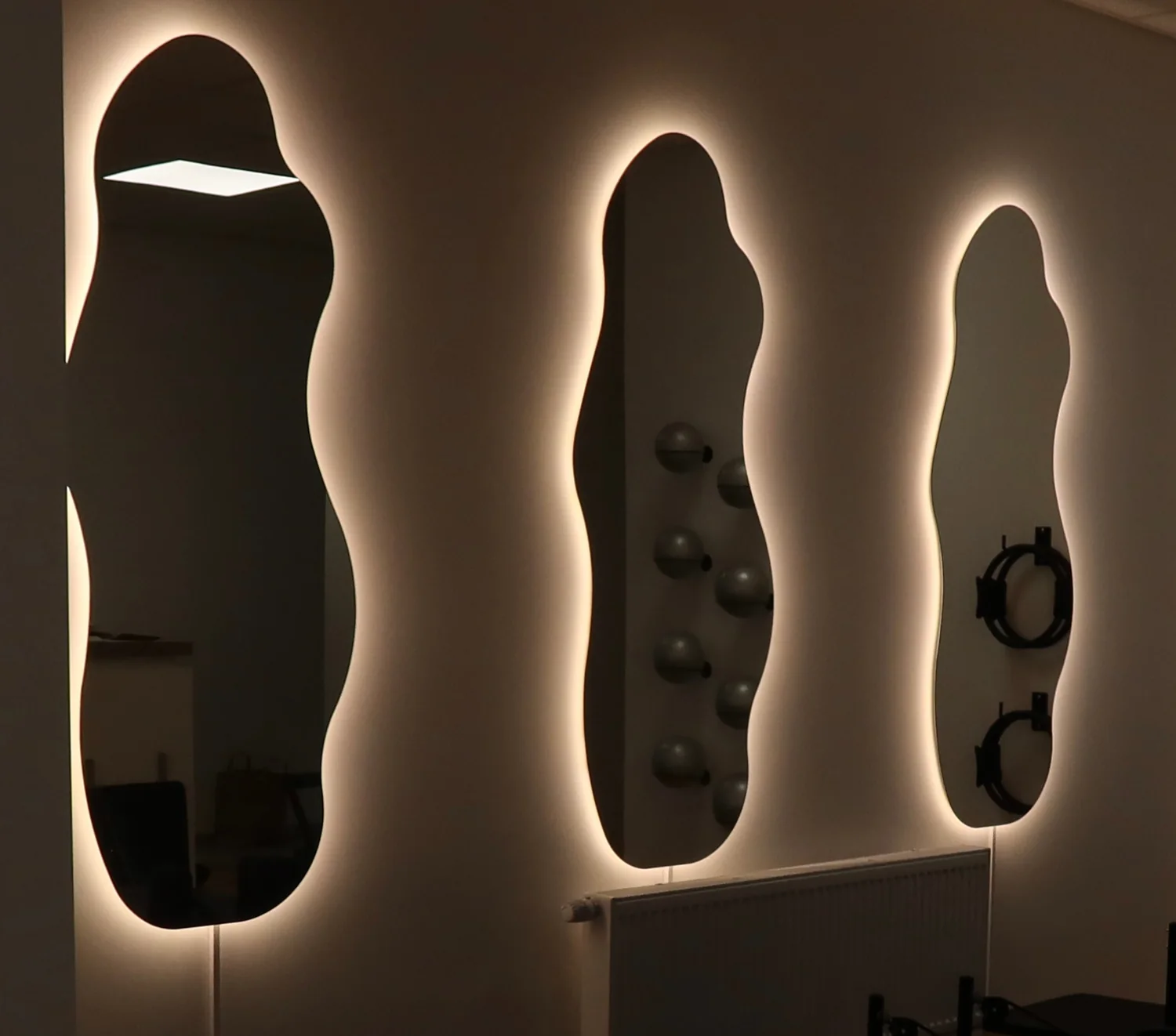 Miroirs ondulants rétroéclairés d'une lumière ambrée dans le studio Sculpt
